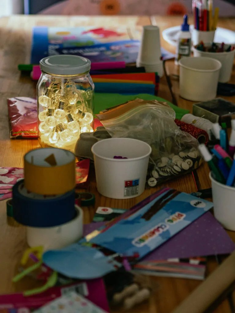 Zestaw materiałów kreatywnych na ławce - słoik z żarówkami, taśmy, kolorowa bibuła, pisaki, klej itd.